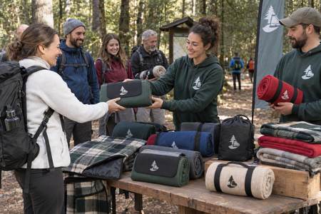 Wanderverein verteilt personalisierte Campingdecken bei einer Wanderung im Wald